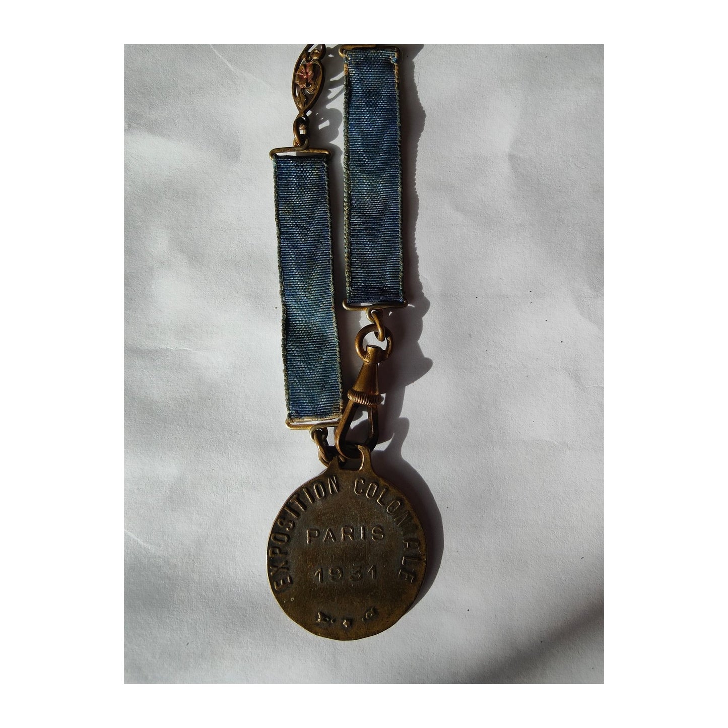 Médaille émaillée de l’Exposition Coloniale Paris 1931, rare et montée sur bracelet articulé tissu/métal, petite pièce historique de 25 mm très recherchée.